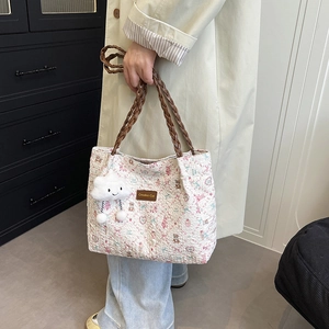 Floral tote bag with bear print and leather straps shown from a stylish side angle