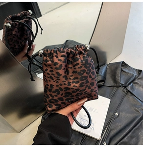 Detail of leopard print bucket bag featuring black drawstring and silver metal ball accents