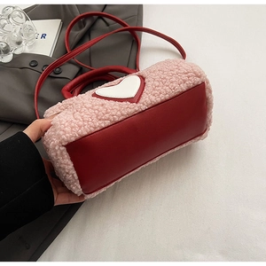 Detail of pink faux fur cylinder bag with red leather base and heart patch decoration