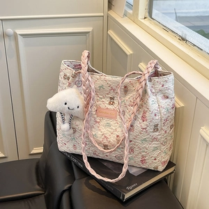 Quilted tote bag with cute animal prints and pink braided handles shown on leather chair