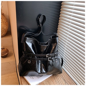 Dettaglio della borsa tote in pelle cerata nera lucida con fibbie a doppio cinturino