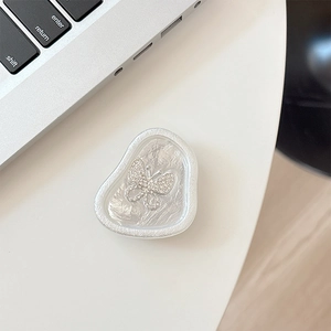 Macro detail of silver rhinestone butterfly phone grip with cloud texture base