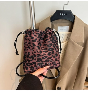 Detail of leopard print drawstring bucket bag featuring leather cord and silver accents