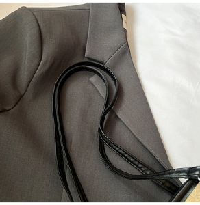 Detail of dark grey twill suit jacket collar with black synthetic leather bag strap