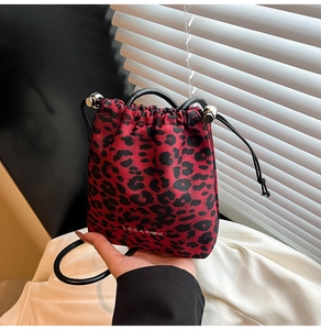 Detail of red and black leopard print bucket bag with drawstring and brand logo