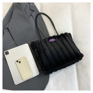 Détail du cabas en peluche noire avec surpiqûres rayées et étiquette mode sur un costume