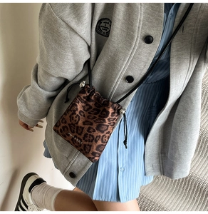 Detail view of leopard print drawstring bucket bag with satin finish and black slim strap