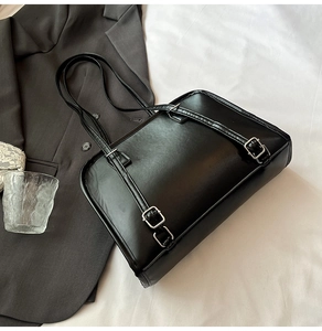Close-up of black PU leather tote bag featuring silver buckles and smooth matte finish