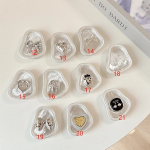 Macro detail of silver metal phone grip charms featuring heart and strawberry designs