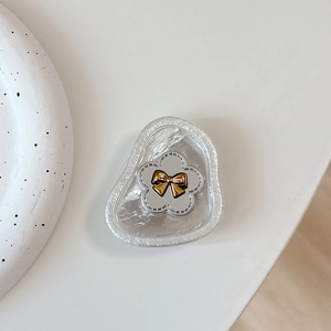 Close-up of floral phone socket with silver flower and golden bow on a pearl texture