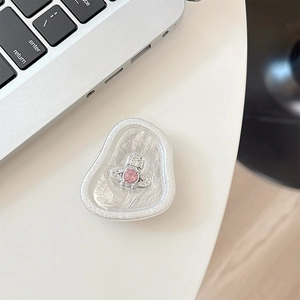 Detail of white pearl texture phone grip with silver saturn orb and pink crystal jewel
