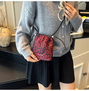 Vue détaillée du sac seau à imprimé léopard rouge porté par un mannequin pour style chic