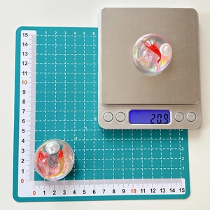 Macro detail of goldfish resin phone grip showing size and weight on a digital scale