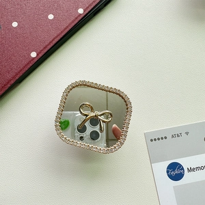 Macro detail of square phone grip mirror featuring a gold bow and crystal rhinestone border