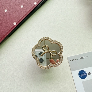 Detailed view of flower-shaped mirror phone grip with crystal inlay and golden bow decoration