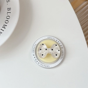 Close-up of a white polka dot bow-shaped MagSafe phone grip on a decorative card