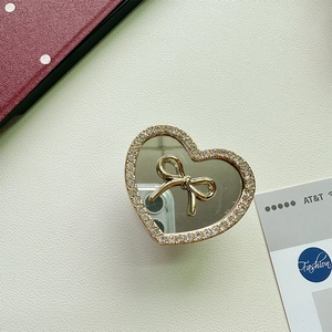 Detailed view of heart-shaped phone grip with gold bow mirror and crystal rhinestones