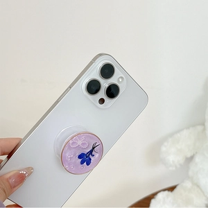 Détail du support téléphone pailleté violet avec fleurs séchées bleues et perles