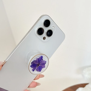 Macro shot of purple dried flower phone socket stand with gold rim on white phone