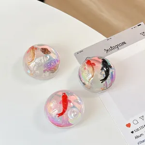Spherical phone socket grips with miniature koi fish, seashells, and iridescent pearly base