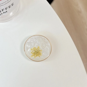 Macro detail of resin phone grip with yellow dried flower, pearls and silver glitter