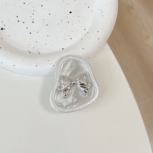 Macro view of silver bow-shaped phone grip on minimalist polka dot ceramic plate