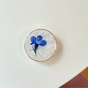 Vue macro du support de téléphone avec fleur séchée bleue, perles et paillettes en résine