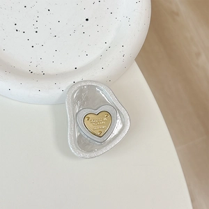 Detail view of heart-shaped phone grip with metallic gold core and pearlescent base