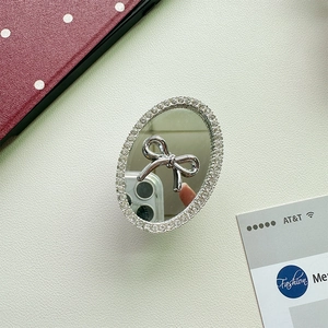 Detail view of oval mirror phone grip with silver bow and sparkling rhinestones on leather