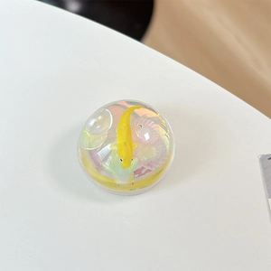 Macro view of a spherical iridescent phone grip with yellow fish and coral miniatures