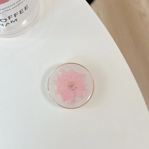 Macro view of a resin phone grip with an embedded real pink flower and gold border