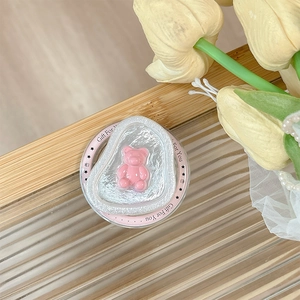 Close-up of pink bear phone grip on textured base with Gift For You inscription