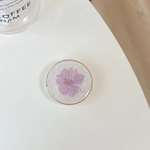 Macro detail of round phone socket featuring real purple dried flower and gold rim