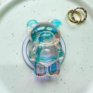 Detailed view of an iridescent bear-shaped magnetic phone grip on a white ceramic plate