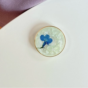 Détail du support de téléphone en résine à paillettes avec fleur bleue et perles