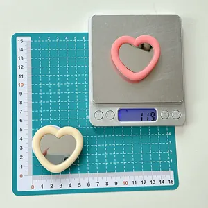 Detailed view of heart-shaped phone grip mirrors weighing 11.9g in pink and cream beige