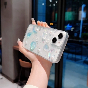 Close-up of sparkling mermaid tail, pearls and heart sequins on transparent phone case
