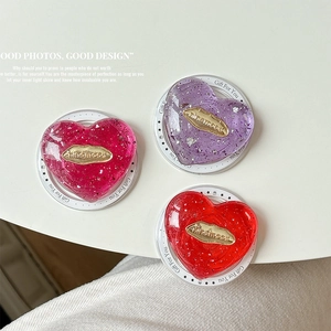 Transparent resin heart phone grip with silver foil and gold metallic logo inlay