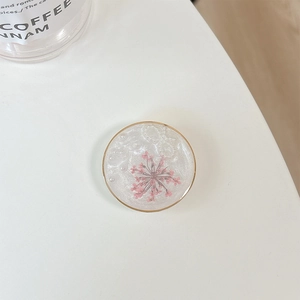 Macro shot of phone grip with real pink dried flower and pearls in resin