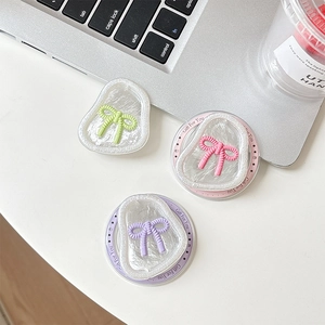 Trois supports de téléphone magnétiques nœud en rose, violet et vert sur bureau