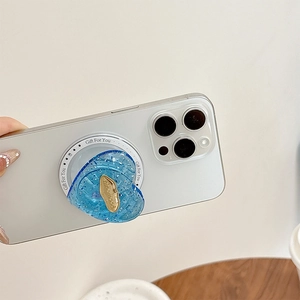 Close-up of heart-shaped glitter phone grip with gold emblem on a white smartphone