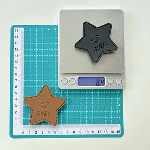 Close-up of star-shaped leather phone grips showing 8.4g weight and 6cm size scale