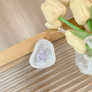 Close-up of a purple resin bear phone grip with a pearlescent wavy base on wood
