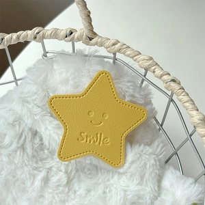 Detail of yellow star-shaped leather phone grip with stitched edges and smile embossing
