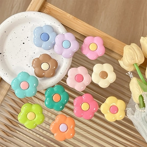 Cute floral phone socket grip in various pastel colors on a decorative ceramic tray
