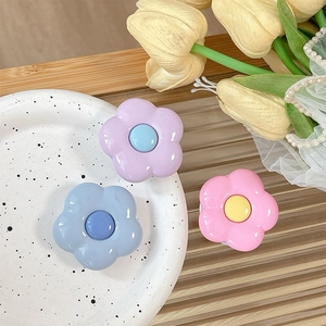 Three colorful floral phone socket grips in purple, blue, and pink on a stylish tray