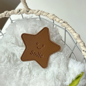 Close-up of brown star-shaped leather phone holder with Smile embossing and stitching