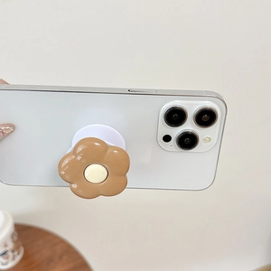 Detail of a brown resin flower phone socket grip mounted on a white smartphone back