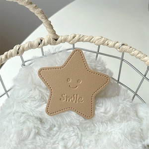 Macro detail of star-shaped khaki leather phone grip with smile embossed on soft fur