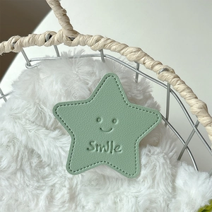 Detail of light green star-shaped leather phone grip with Smile face and fine stitching